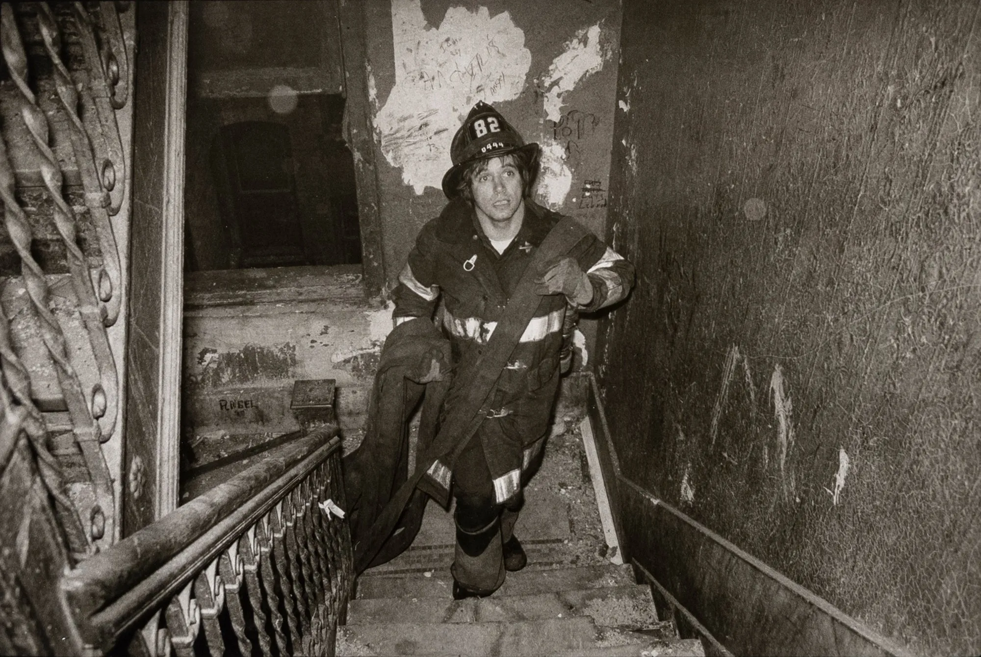 Untitled [A firefighter carries the fire hose nozzle upstairs in an apartment block in the South Bronx, New York City]